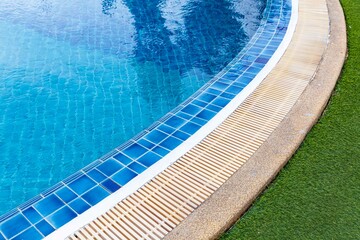 Wide swimming pool and green artificial turf inside the villa