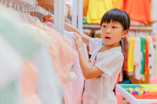 Asian little girl choosing clothes in clothing store