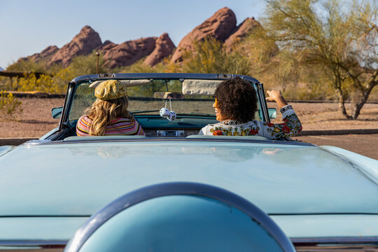Happy Friends Talking in Vintage car with fuzzy dice 