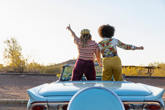 Two Friends Dancing in Convertible Car looking out at Arizona landscape, 