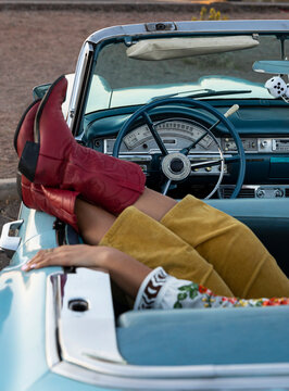 Young Cool  Girl Relaxing on Backseat of Convertible car with Red Cowboy Boots 