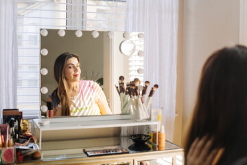 Woman with charming makeup and smile looking in mirror