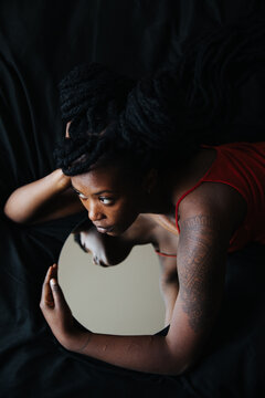 Pensive black girl hugging a mirror