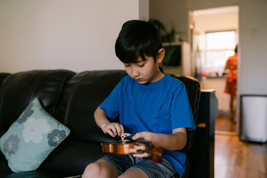 young boy tuning his violin 