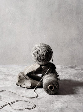 Still life setup of grey yarn and rock on marble grey backdrop
