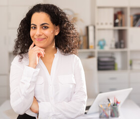 Confident young woman posing in office of international company