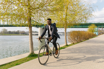 Young african american businessman riding a bicycle to work in the urban city zone 