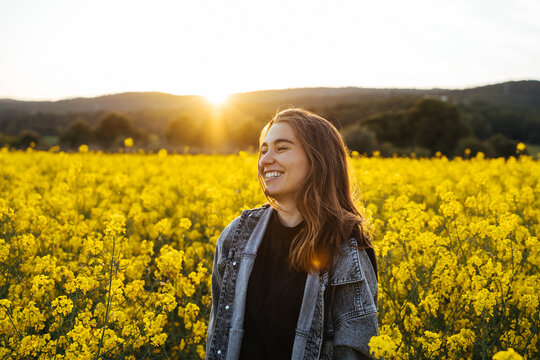 Happy Young woman in flowers field during sunset