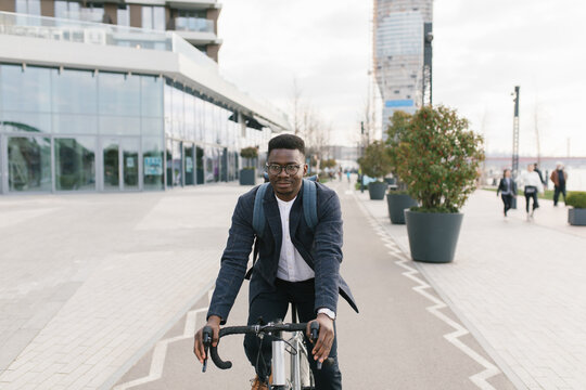 Young african american businessman riding a bicycle to work in the urban city zone 