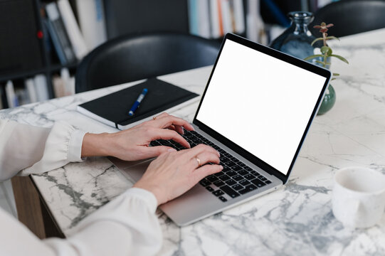Crop businesswoman typing on laptop with empty screen