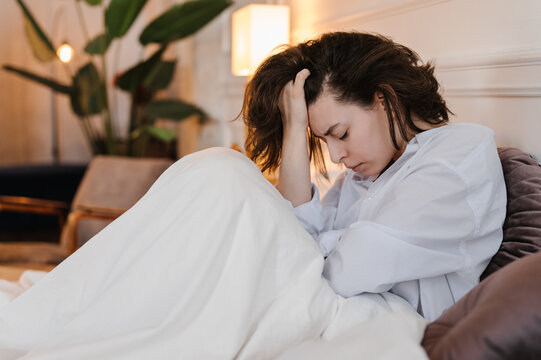 Unhappy female touching hair on bed