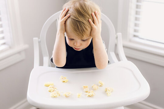 Overwhelmed toddler with hands on his head