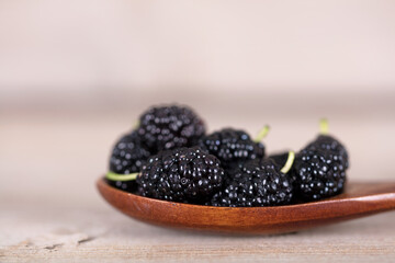 A spoonful of fresh mulberries on a wooden background
