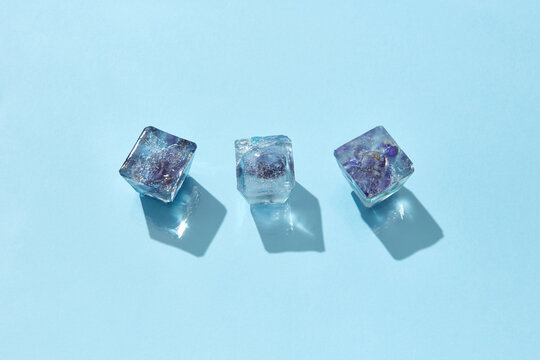Three ice cubes with violet flowers