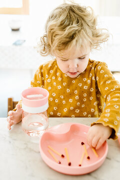 Blond child eating 'matches' made from cheese and pomegranate