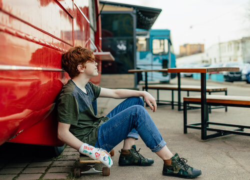 A teenager with a bandage on his arm and a skateboard