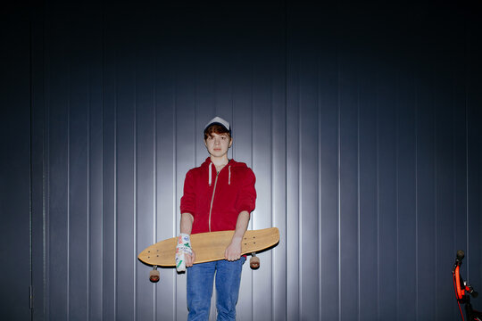 A teenager with a bandage on his arm and a skateboard