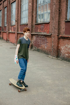 A teenager with a bandage on his arm and a skateboard