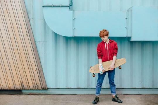 A teenager with a bandage on his arm and a skateboard