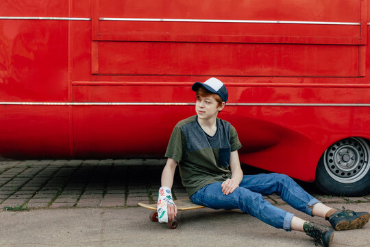 A teenager with a bandage on his arm and a skateboard