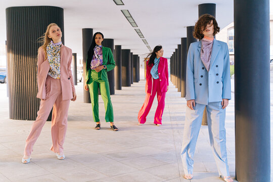 Confident multiracial women in suits standing near columns