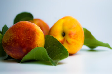 Fresh juicy nectarine with green leaves on a white.