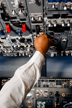 Crop black pilot pushing switches in cockpit