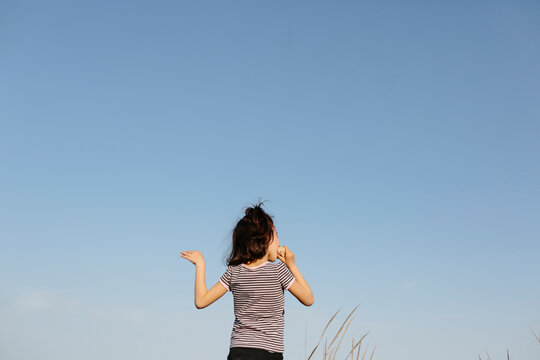 Back of kid eating a sandwich over sky background