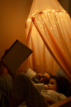 Father and daughter reading a story in bed