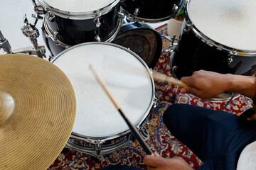 Crop black man playing drums over carpet