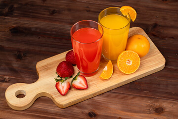 Strawberry and orange juice glass decorating with fresh fruit on wooden cutting board over wooden...
