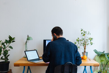 Unrecognizable adult man talking on the phone while sitting at home office