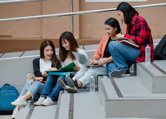 Group of four attractive asian college students sitting down on each staircases in university campus studying outdoor. Concept for education, friendship and college students life