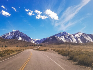 Road to Snow capped Sierra Nevada Mountains blue sky with clouds