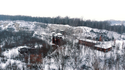 Drone view of Liban quarry Kamieniolom in Krakow, Poland during the winter season. Old rusty machinery and piping equipment in closed limestone. Evergreen trees in the background against clear white