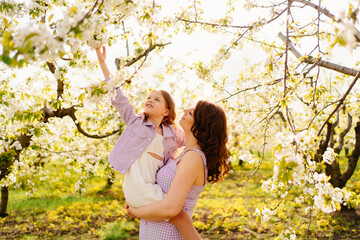 mom and daughter. family in purple clothe in blossoming spring garden.