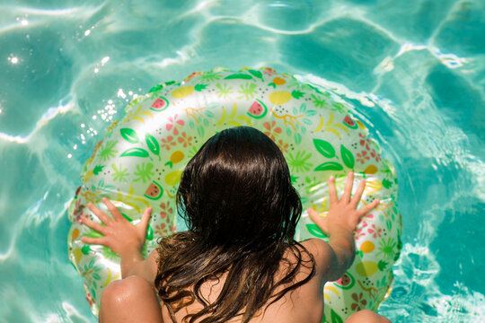 Pre Teen Girl Swimming and Jumping on a Floatie in the Pool