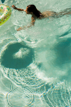 Pre Teen Girl Swimming and Jumping on a Floatie in the Pool