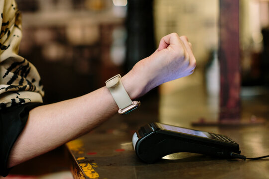 Detail shot of hand wearing a smart watch doing a wireless payment at a restaurant
