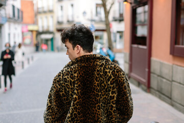 Back view of young gay attractive person walking in the cit street