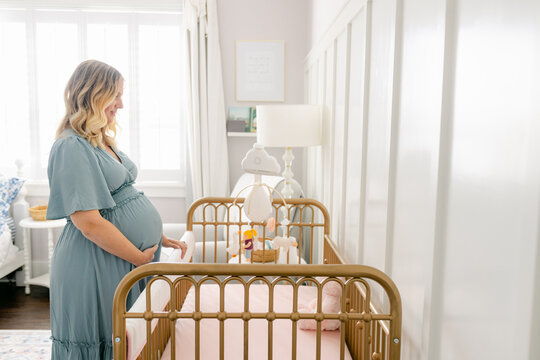 A pregnant woman looks longingly at her crib
