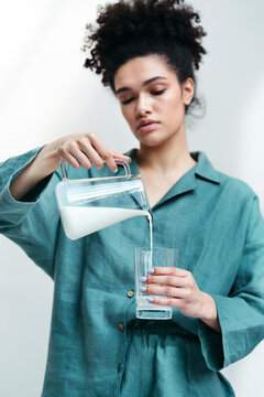 A young woman pours milk from a glass jug.