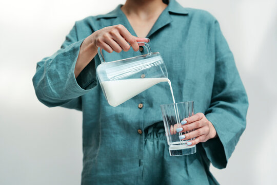 A young woman pours milk from a glass jug.