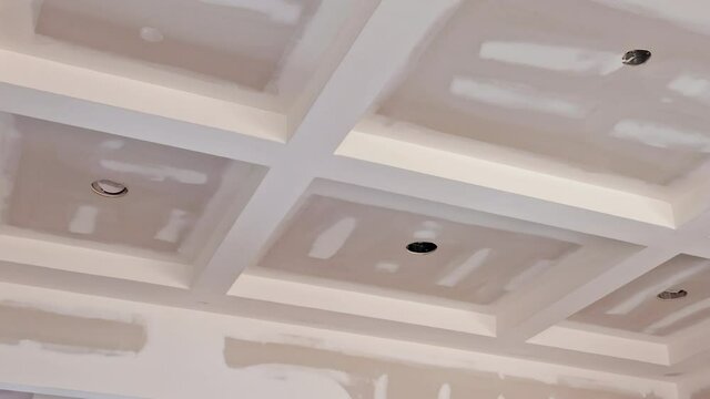 Finishing putty on drywall with a spatula the house on ceiling and wall