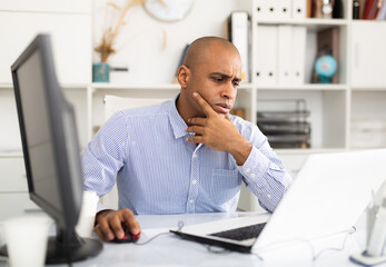 Frustrated tired office manager working at laptop