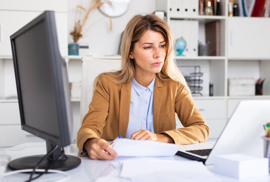 Woman working with papers and laptop in office