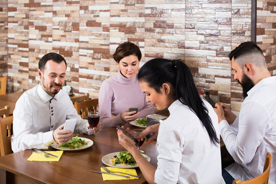 group of friends busy with phone ignoring dinner in restaurant