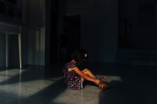 Child pouting sitting on the floor. 