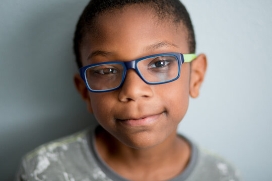 Boy with glasses peers up at camera