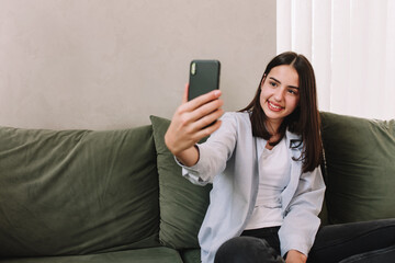Naklejka premium Smiling teenager posing a smile and taking a selfie with smartphone